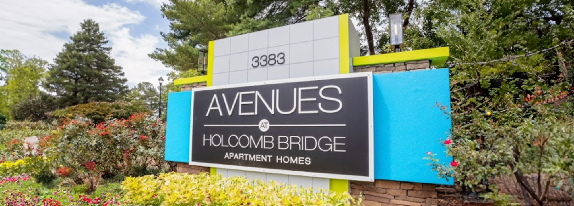 The image shows a real estate sign for  Avenues Apartments,  with the text  338 1 2  and an address  HOLYMORE ROAD.  The sign is set against a backdrop of greenery and clear skies.